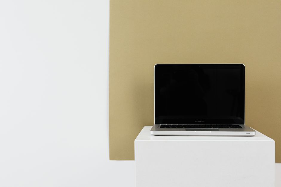 Minimalist photo of a laptop with blank screen on a white stand with ample copy space.